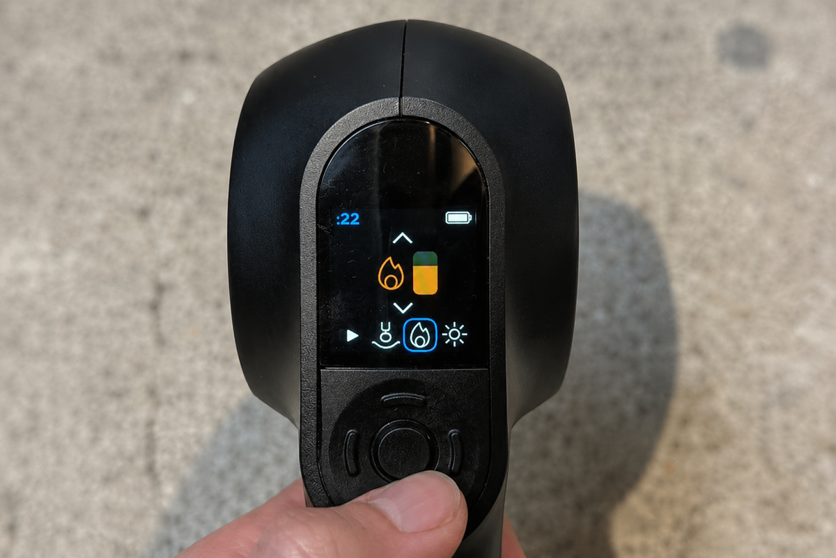Close-up of a handheld massage gun digital display showing heat and intensity settings.