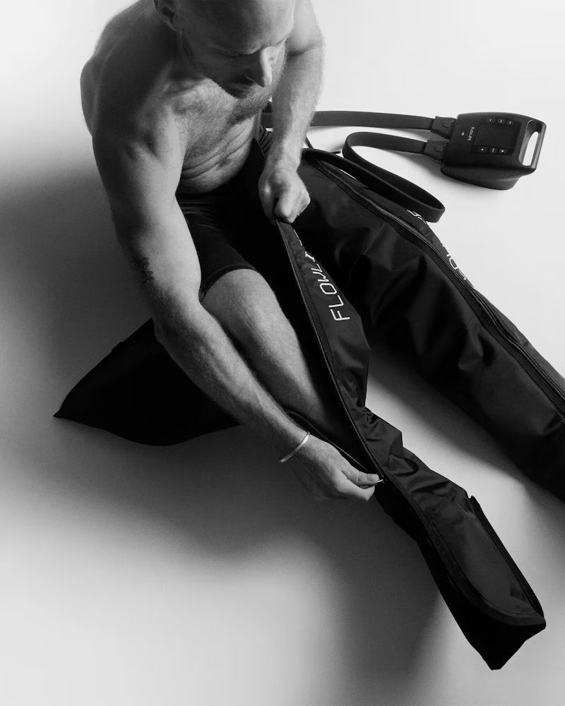 Man using Flow leg compression recovery boots for athlete performance and injury prevention