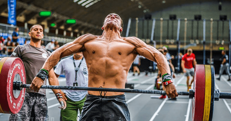 Male athlete performing Olympic weightlifting snatch lift in functional fitness competition