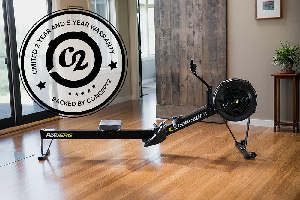 Concept2 RowERG indoor rowing machine in home gym with warranty badge overlay