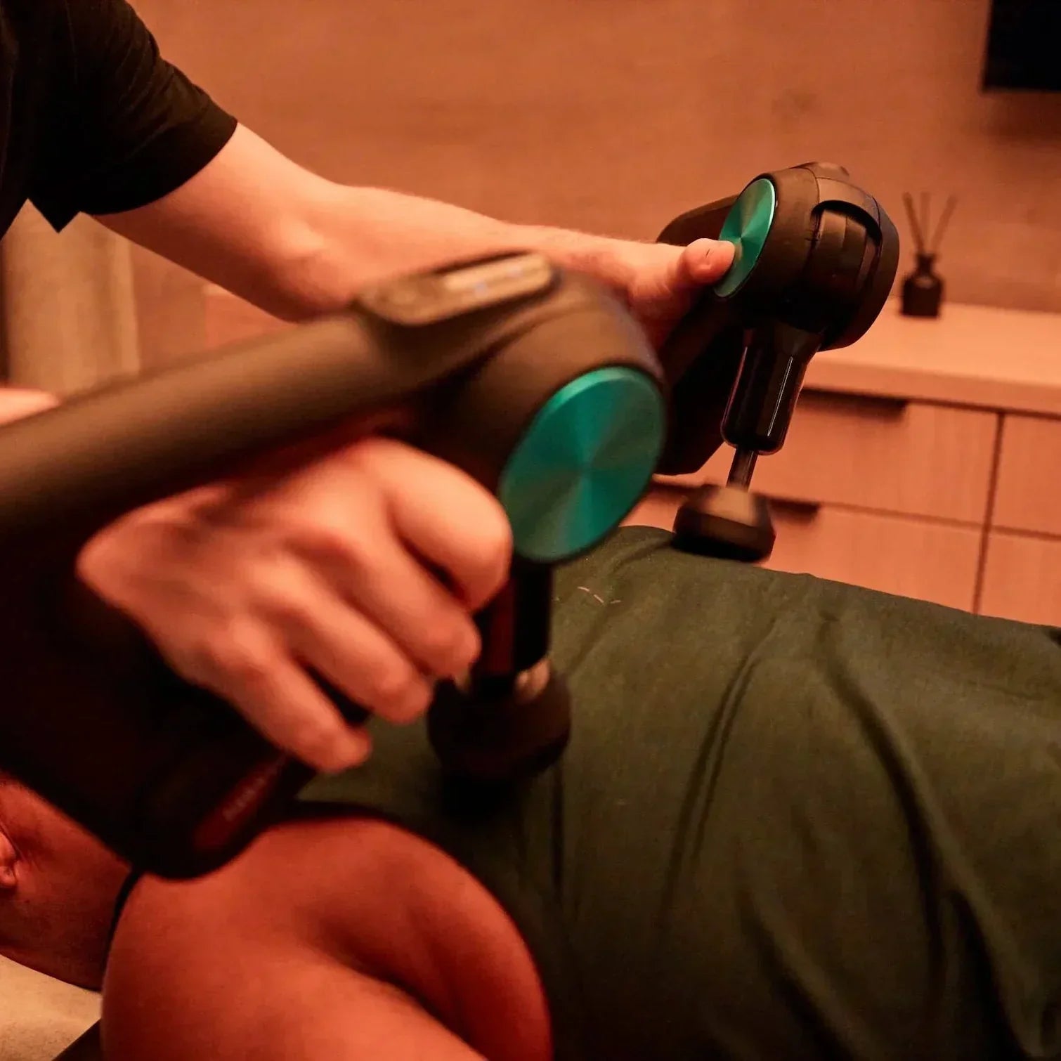 Person using two massage guns on upper back for muscle recovery in fitness setting