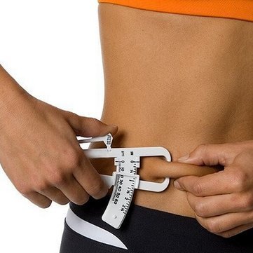 Woman measuring body fat with skinfold caliper, fitness and health concept