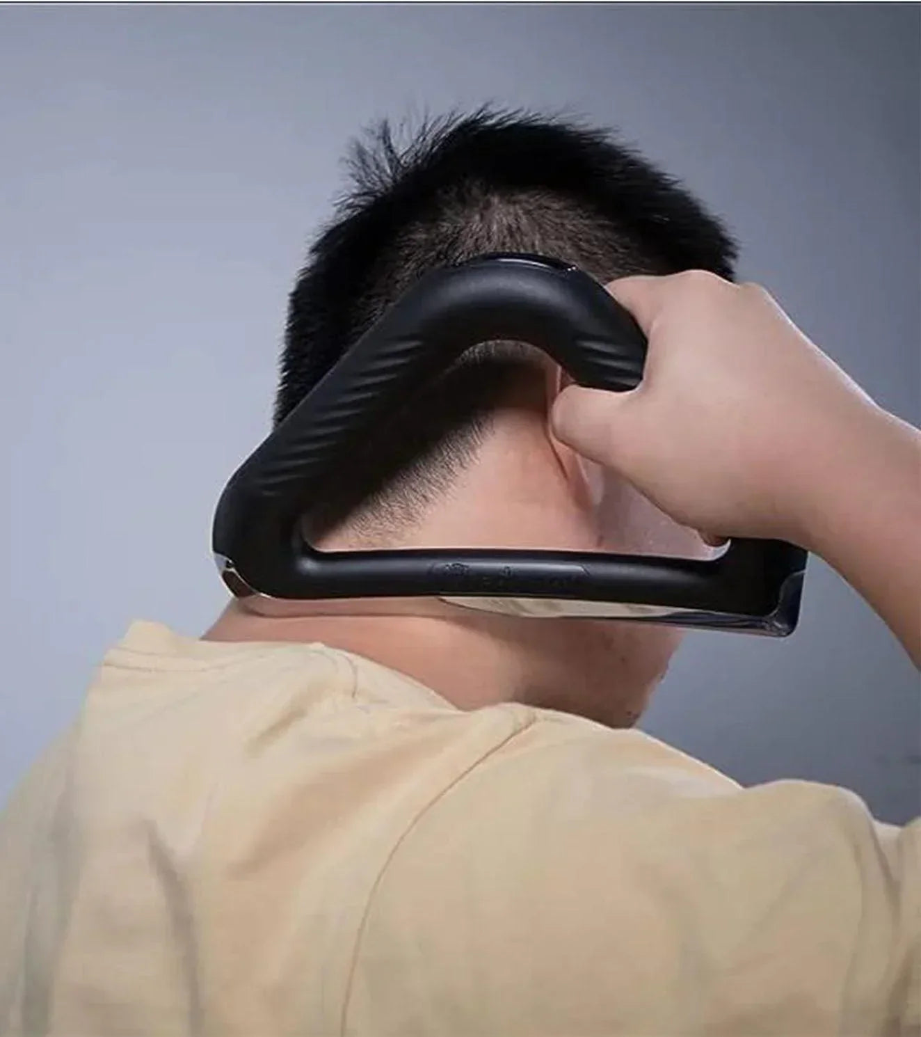 Person using a black heated muscle scraper tool on neck for muscle recovery