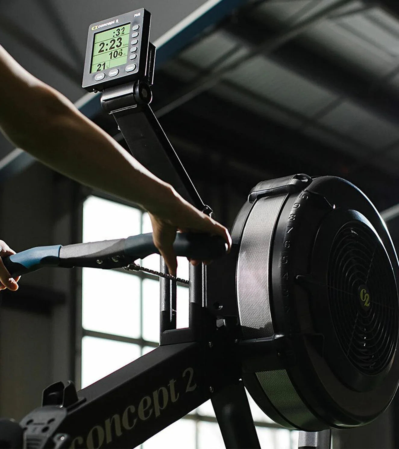 Athlete using Concept2 rowing machine with digital display in gym setting