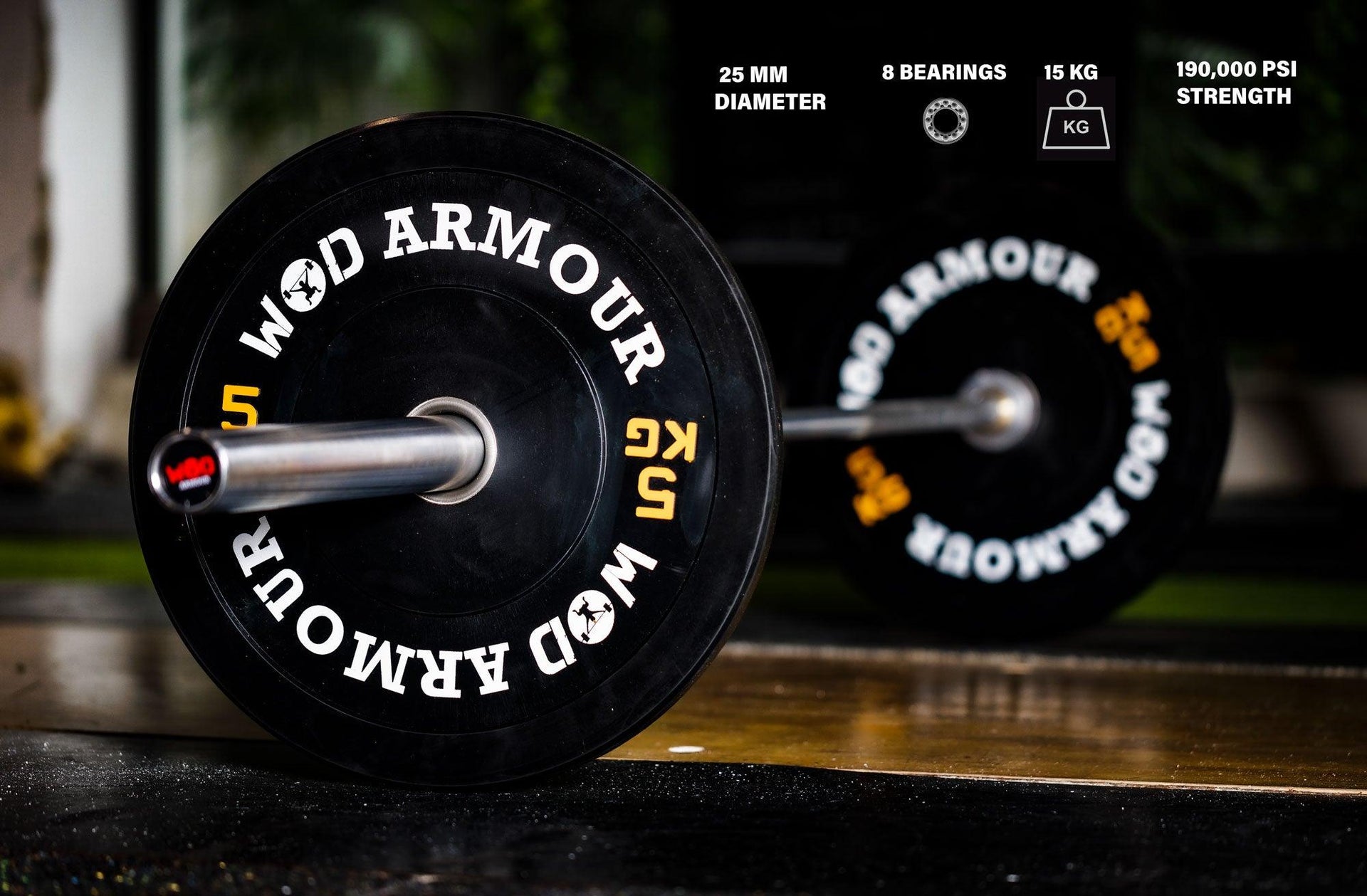 Close-up of a CrossFit barbell with black plates on a gym floor, 15kg, 25mm diameter.
