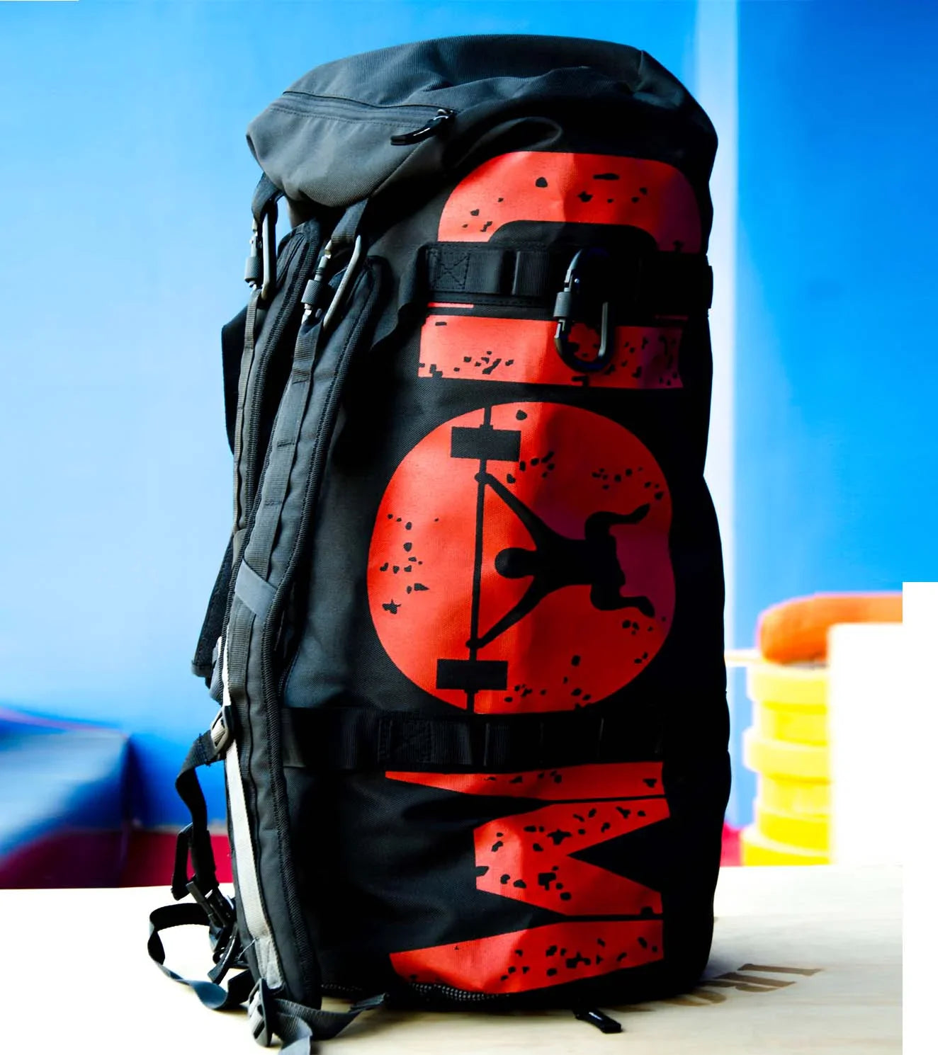 Large black gym travel bag with red weightlifting graphic, set on a light wooden table