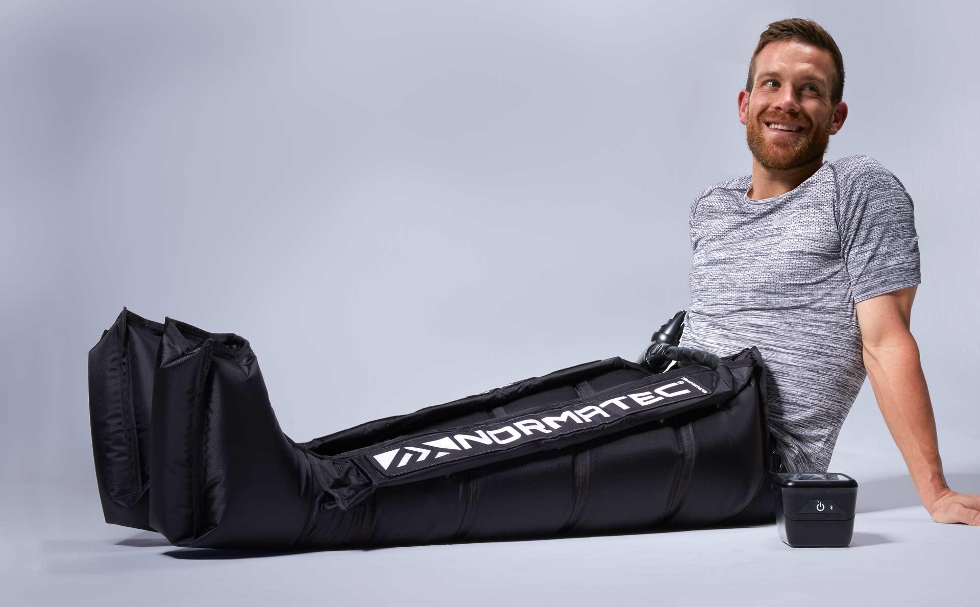 Athlete using Normatec leg compression recovery device for fitness muscle recovery