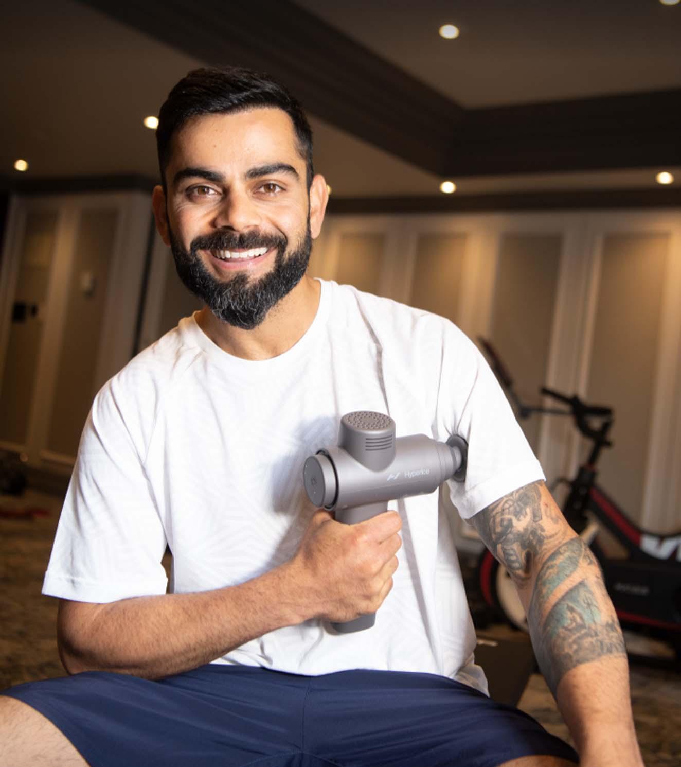 Man using massage gun for muscle recovery in gym setting, fitness and physiotherapy.