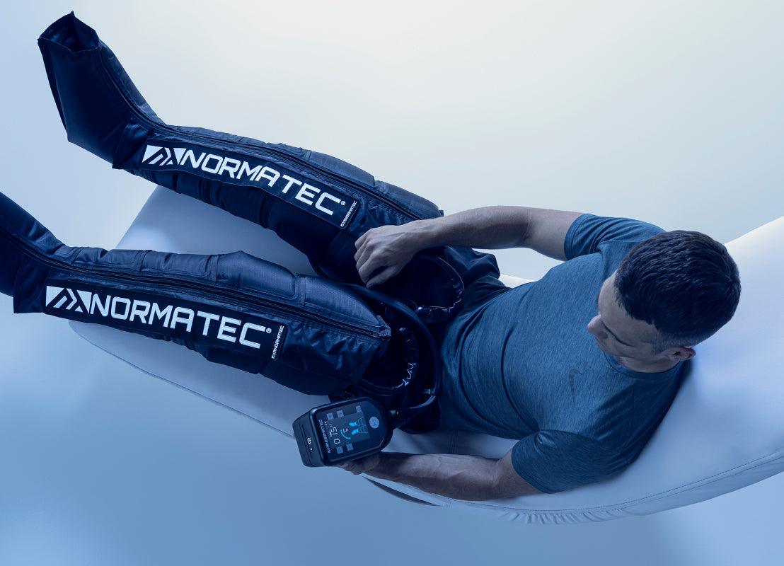 Man using NormaTec compression recovery boots for lymphatic drainage therapy
