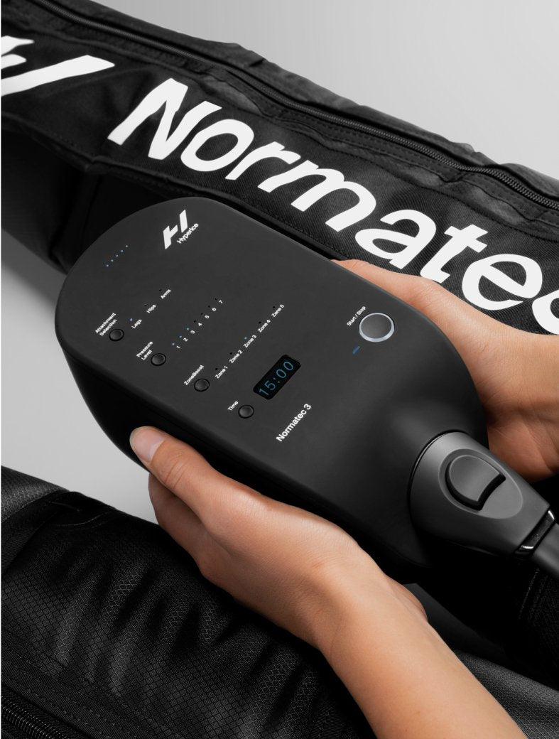 Person holding Hyperice Normatec 3 leg recovery system control panel on black sleeve