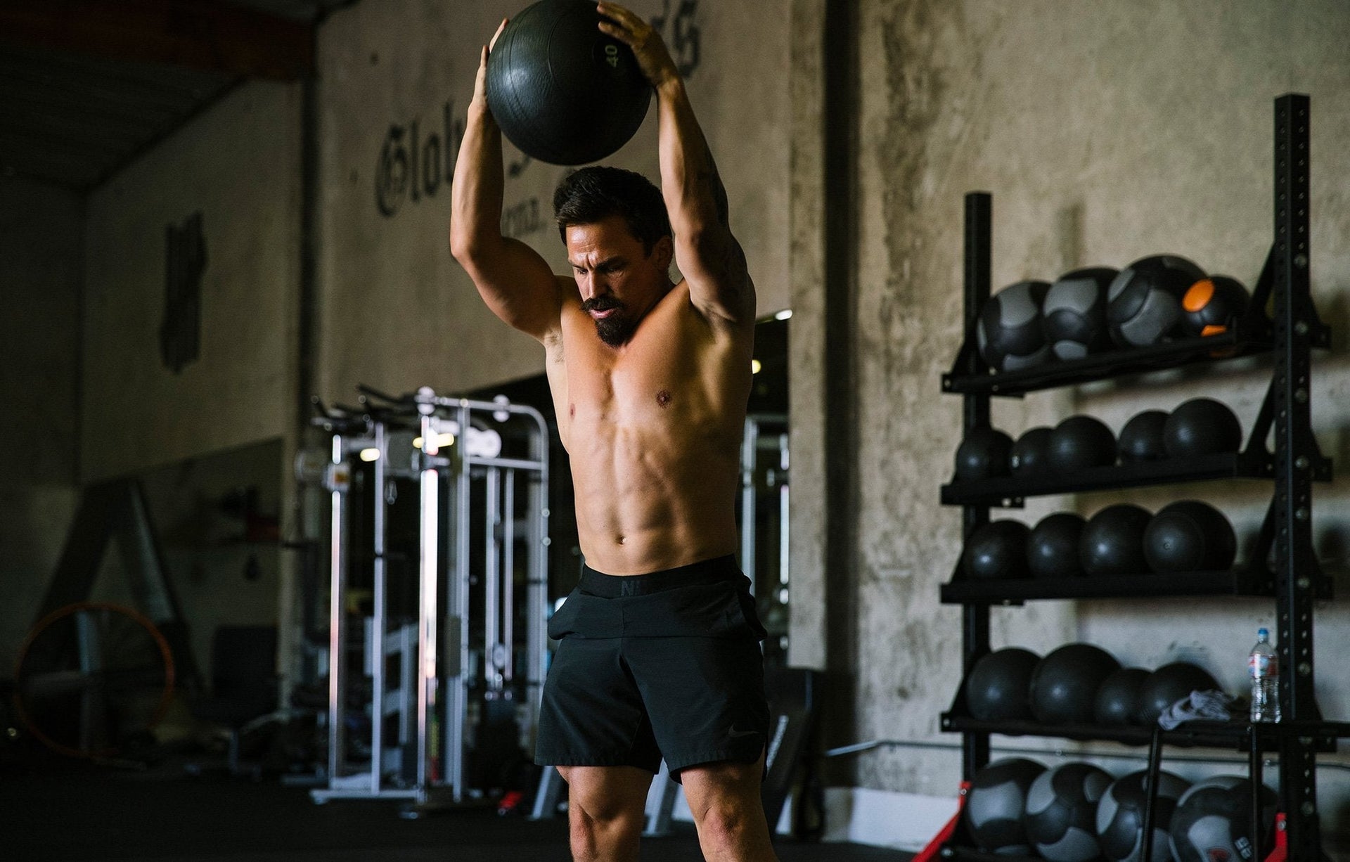 Athlete performing medicine ball slam in a gym, showcasing functional fitness training.
