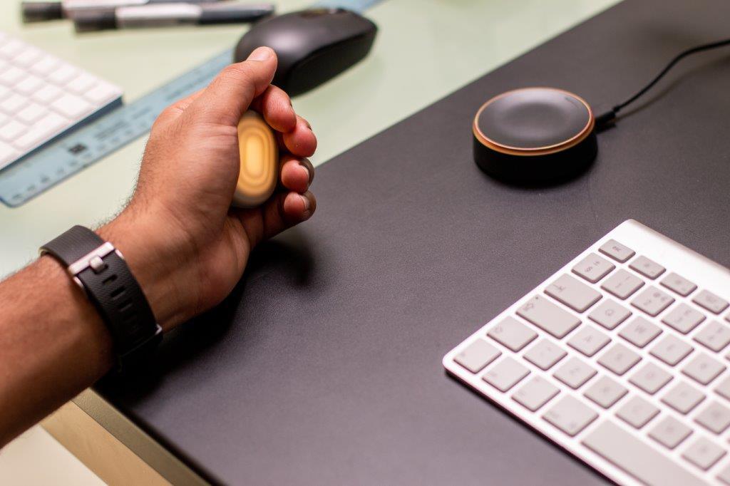 Person using ergonomic stress ball at office desk with computer keyboard and mouse