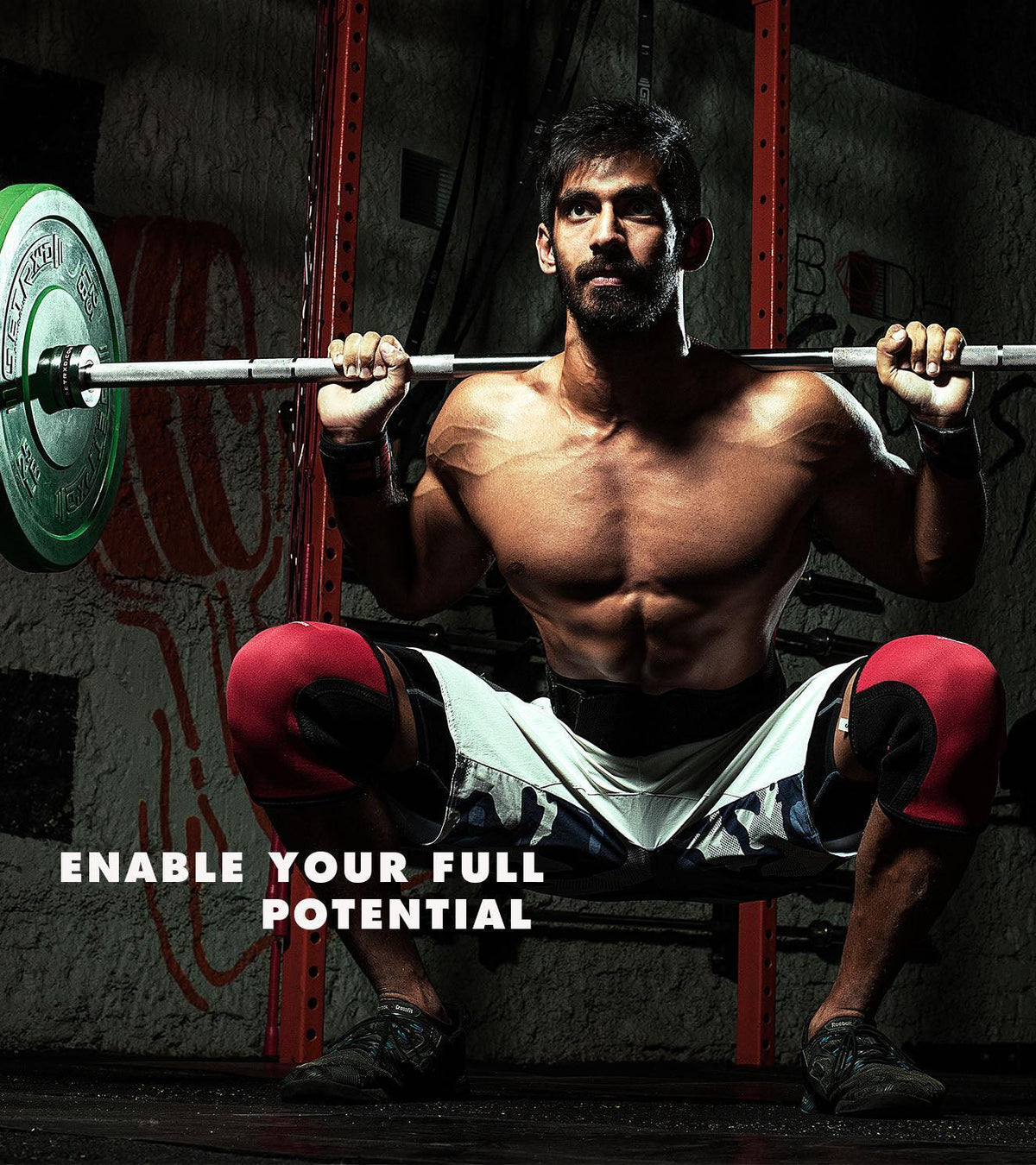 Muscular athlete performing a barbell squat wearing red knee sleeves and lifting gear.