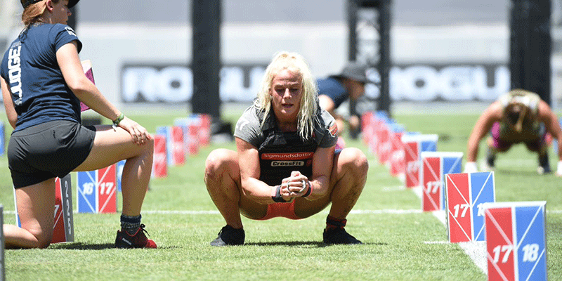 Athletic women performing bodyweight squats during a CrossFit outdoor competition event