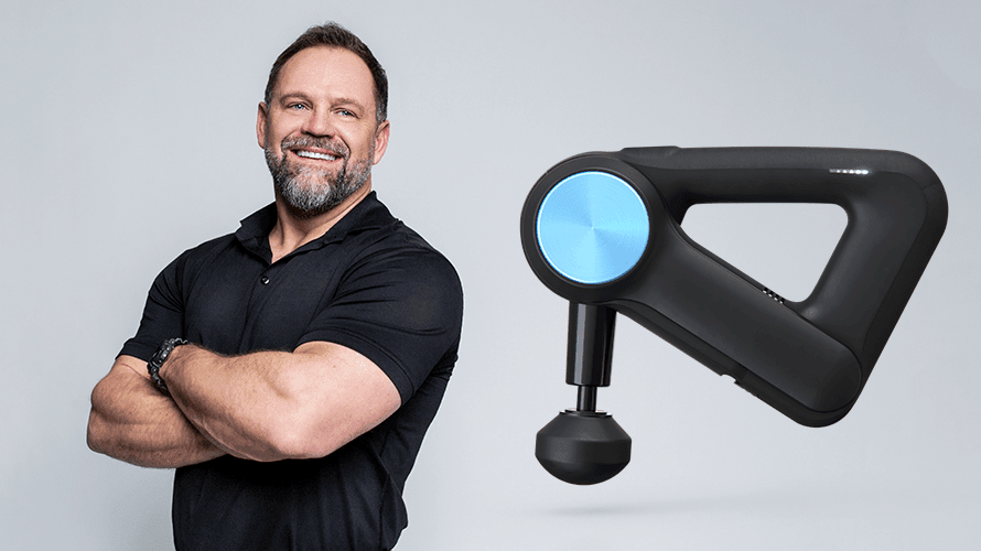 Smiling man in black polo shirt next to a modern percussive massage gun on gray background