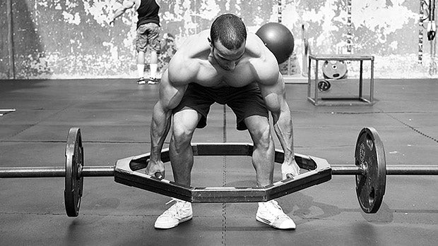 Man performing deadlift with trap bar in functional fitness gym setting