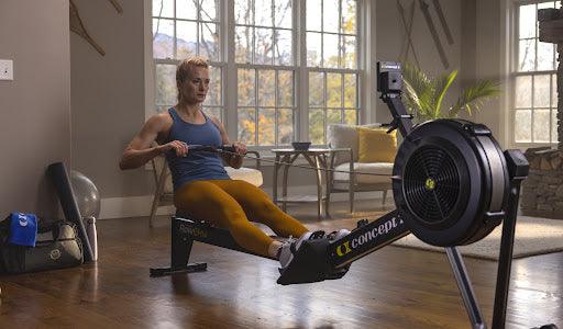 Woman using Concept2 indoor rowing machine in a bright home gym setting