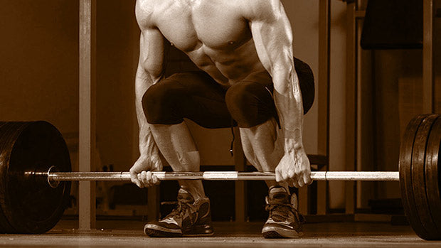 Athlete preparing to deadlift heavy barbell in gym, demonstrating proper lifting form