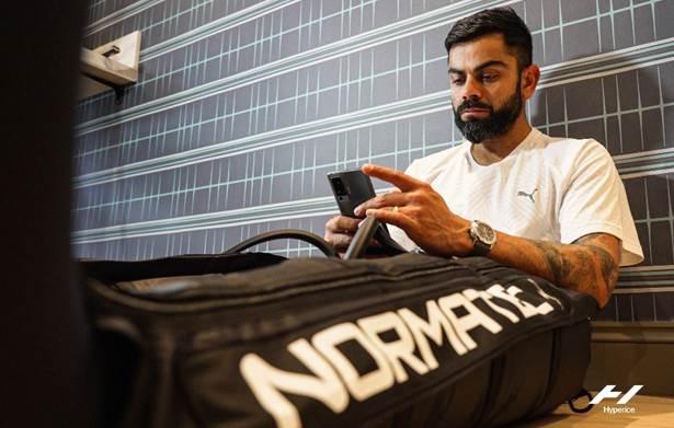 Athlete using phone next to Normatec recovery equipment in modern fitness setting