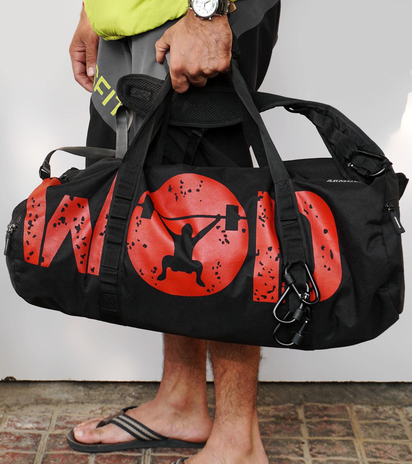 Man holding black gym duffel bag with red weightlifter graphic and WOD text