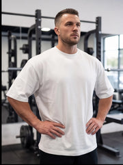 Athlete in white performance t-shirt at gym, hands on hips, ready for functional fitness training