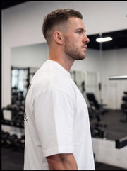 Man in white fitness t-shirt at gym, showcasing athletic wear for functional training and performance