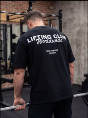 Man lifting barbell in gym wearing black 'Lifting Club Worldwide' WOD Armour t-shirt, functional fitness apparel