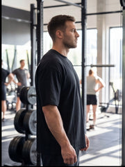 Athlete in black workout shirt at functional fitness gym with weight racks and mirrors