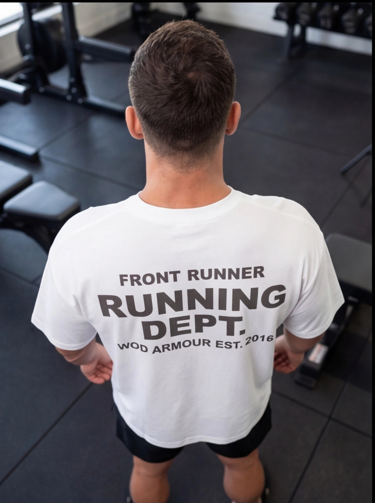 Man wearing white 'Front Runner Running Dept.' gym t-shirt in fitness studio, functional training apparel