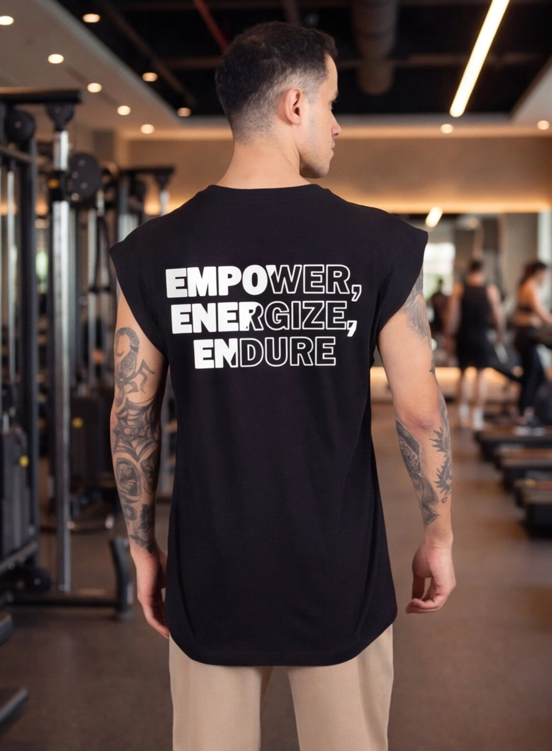 Man wearing black sleeveless gym shirt with 'EMPOWER, ENERGIZE, ENDURE' text, in fitness studio
