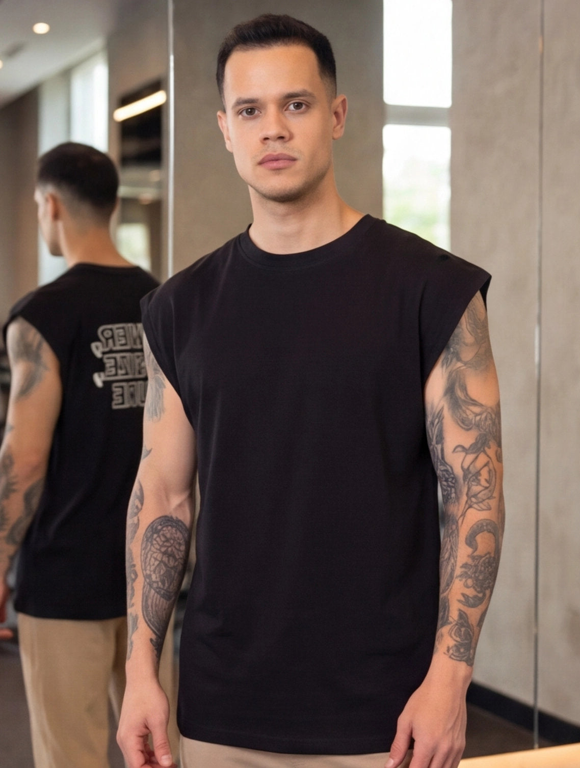 Man wearing black sleeveless gym shirt with tattooed arms, ideal for functional fitness training