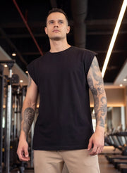 Man in black sleeveless gym shirt with tattoos, standing in fitness studio for functional training