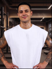 Man in white sleeveless gym shirt, sweating after workout, tattoos visible, functional fitness apparel
