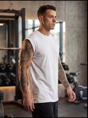 Man in white sleeveless gym shirt with tattoos, standing in fitness studio for functional training