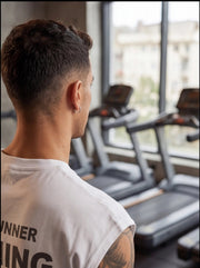 Man in gym wearing athletic shirt, facing treadmills near window for functional fitness training