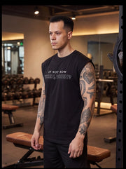 Man in gym wearing black sleeveless fitness shirt with motivational quote 'If Not Now, Then When?' for functional training.