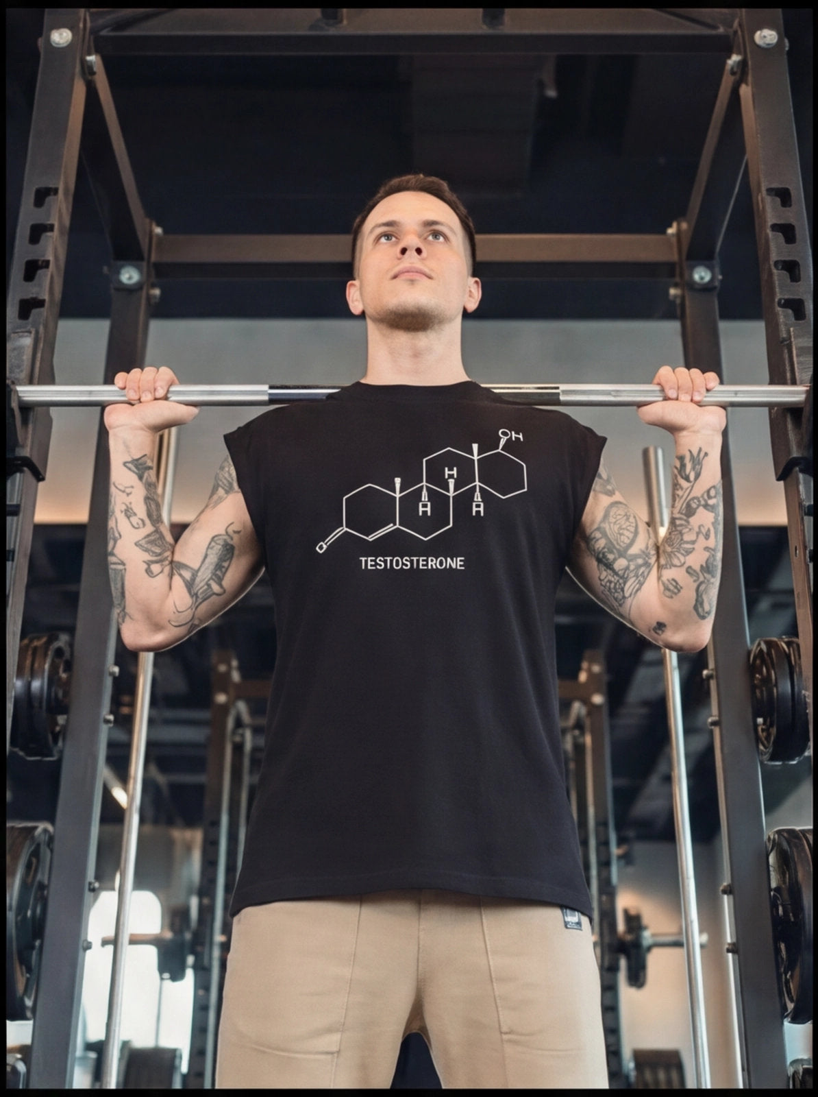 Man in gym wearing black testosterone molecule graphic tee during barbell workout
