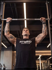 Athlete performing pull-up on gym bar, wearing HYBRID ATHLETES CLUB tank top, showcasing functional fitness training.