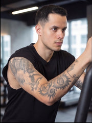 Tattooed athlete in black sleeveless shirt training in gym for functional fitness performance