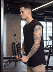 Man with tattooed arms using cable machine for functional fitness workout in gym