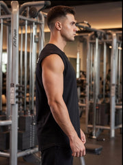 Athlete in black sleeveless gym shirt standing in fitness center with weight machines