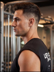 Athlete in black sleeveless gym shirt, side profile in fitness studio