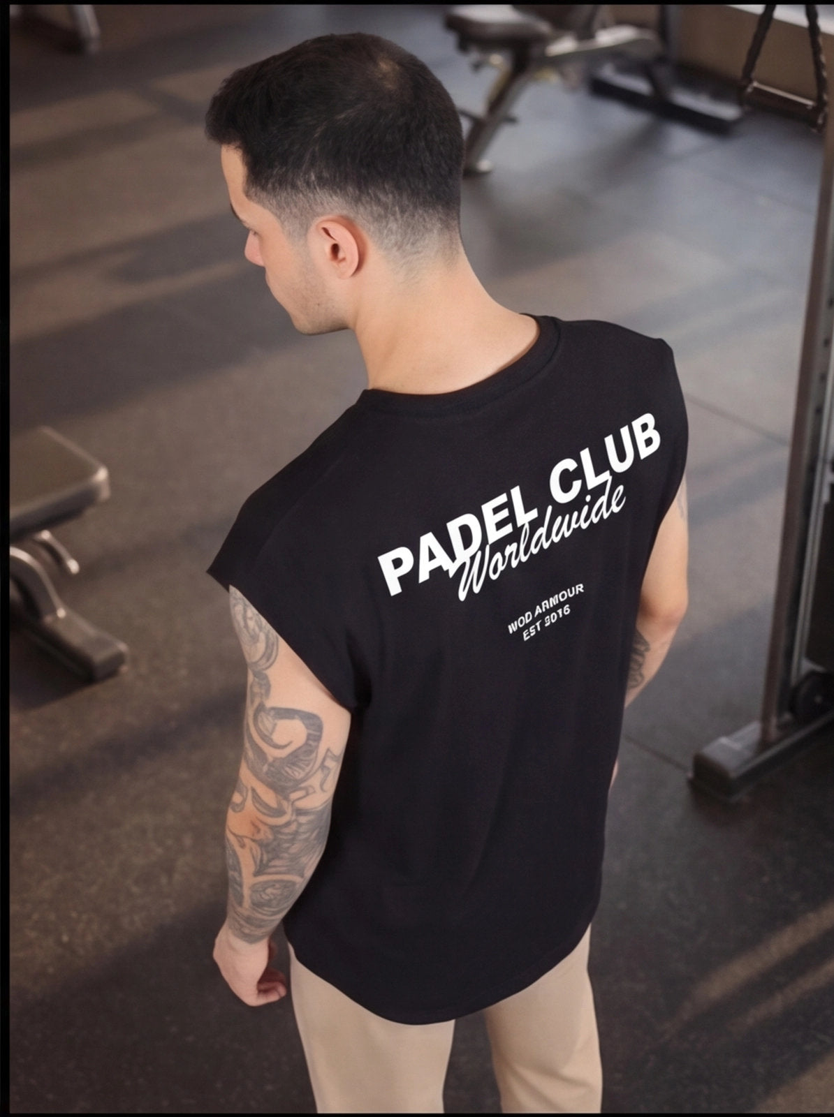 Man wearing black Padel Club Worldwide gym shirt, tattooed arms, functional fitness apparel