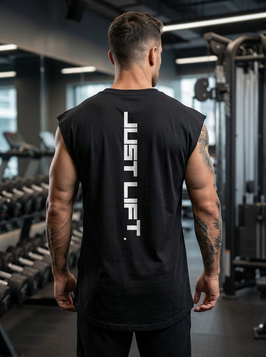 Man wearing black 'JUST LIFT' gym tank top, showcasing athletic build in fitness center