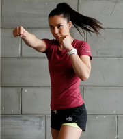Athletic woman in gym shorts punching, functional fitness workout against concrete wall