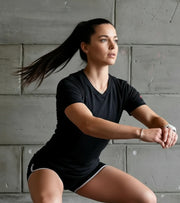 Woman in activewear performing squat exercise indoors against concrete wall, functional fitness