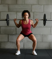 Woman performing barbell squat in gym, functional fitness, athletic training
