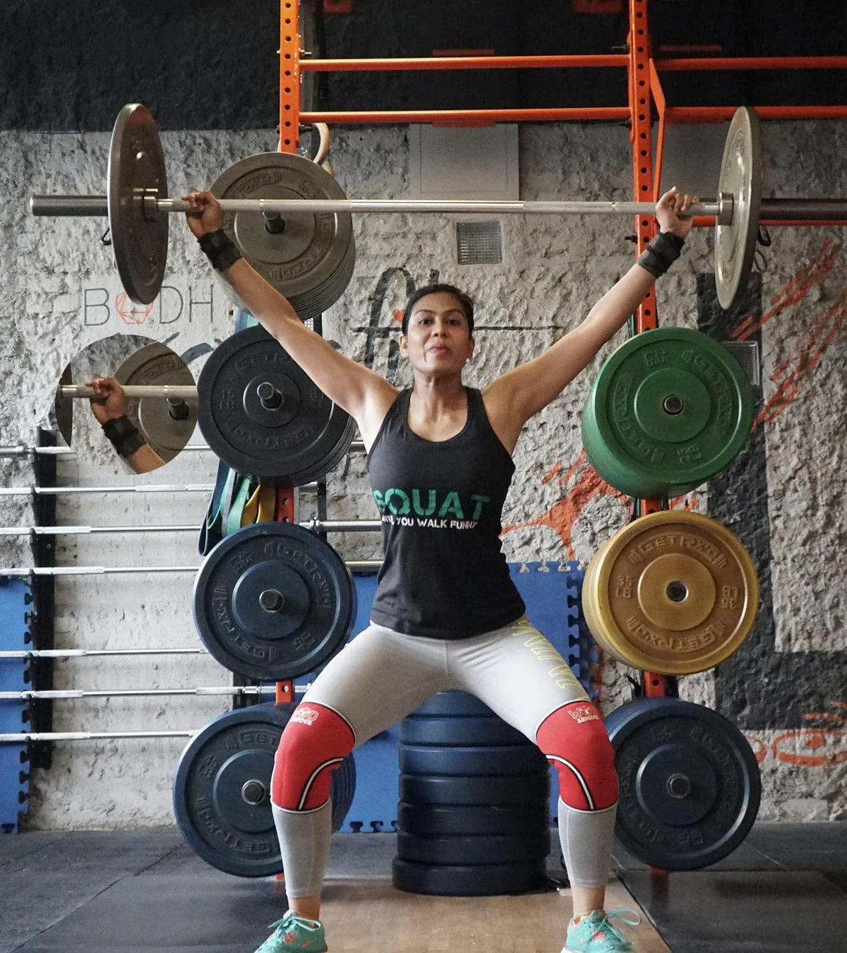Woman in fitness gear holding a barbell overhead in a functional training gym