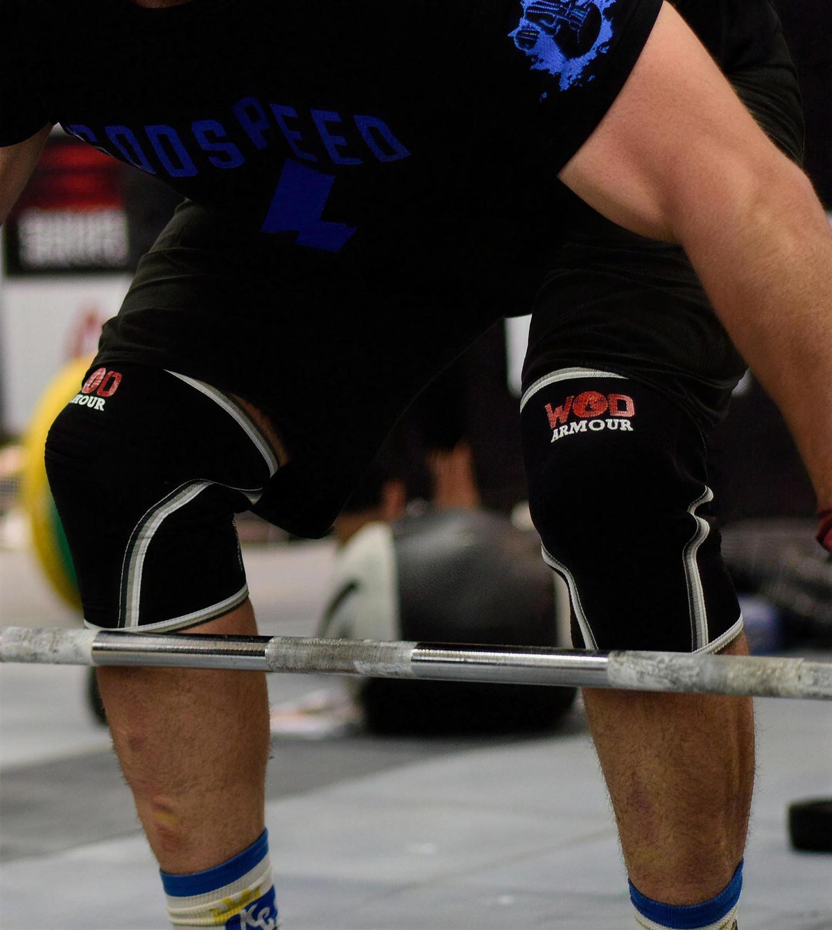 Athlete wearing black WOD ARMOUR knee sleeves while lifting a barbell.